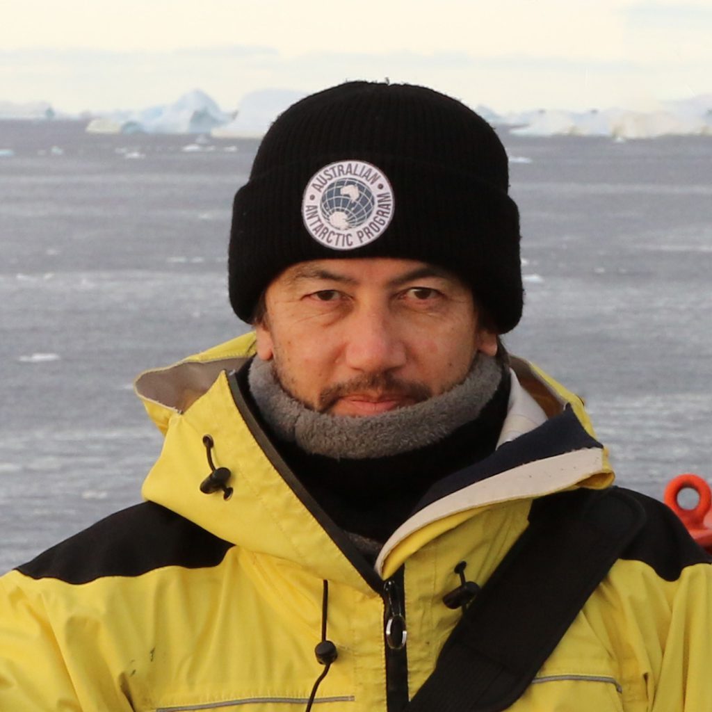 John wearing yellow coat and black beanie aboard vessel in the Antarctic region